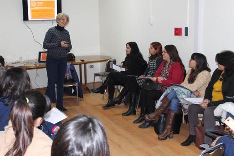 Una mujer está dando una presentación a un grupo de mujeres sentadas en una sala.