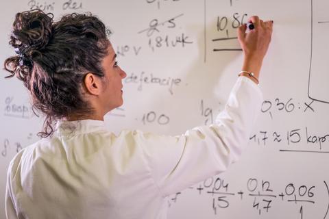 Una mujer escribe fórmulas matemáticas en una pizarra.