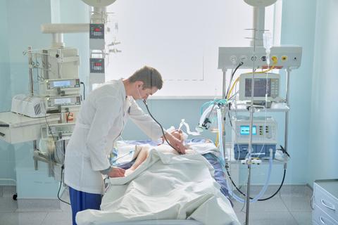 Un médico examina a un paciente en una sala de cuidados intensivos.