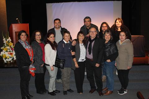 Un grupo de personas posando juntas en un escenario con fondo iluminado.