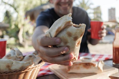 Un compadre disfrutando de una empanada en una tarde de campo.