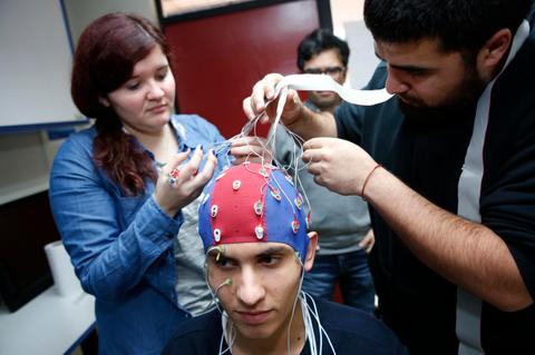 Un grupo de personas está ajustando un electroencefalograma en la cabeza de un joven.