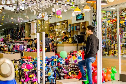 Una tienda colorida llena de juguetes y artículos variados, con personas interactuando en el interior.