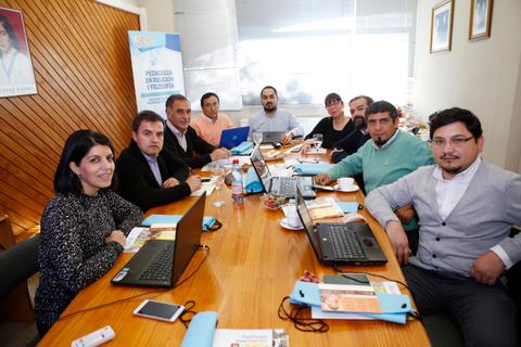 Un grupo de personas se reúne alrededor de una mesa con computadoras portátiles y tazas de café.
