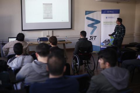 Un grupo de estudiantes asiste a una presentación en un aula con un proyector.