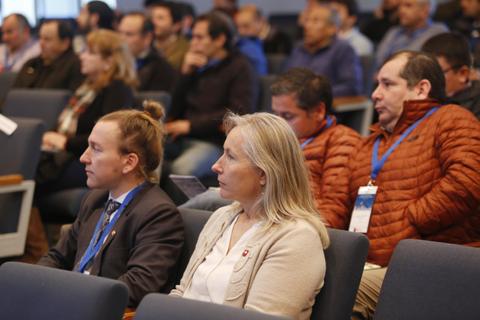 Un grupo de personas sentadas en un evento, prestando atención al orador.
