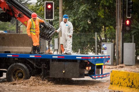 Un camión de rescate está en medio de una inundación mientras dos trabajadores lo operatorios intentan controlar la situación.
