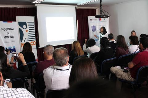 Una presentación en un auditorio con varias personas escuchando atentamente mientras se proyecta una diapositiva.