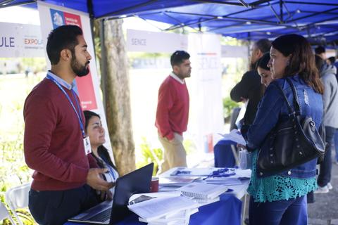 Una feria con diversas personas interactuando en un stand informativo.