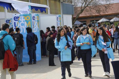 Un grupo de estudiantes camina hacia un evento educativo mientras otras personas se agrupan en el fondo.