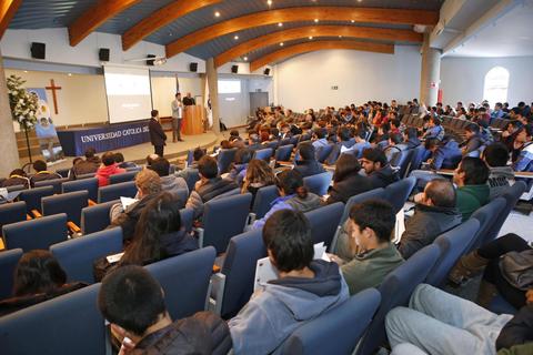 Una conferencia en un auditorio de la universidad con una gran cantidad de asistentes.