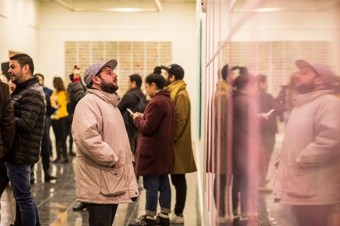 Un grupo de personas observa obras de arte en una galería.