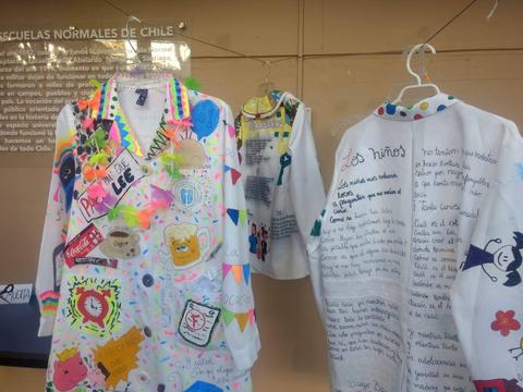 La imagen muestra un conjunto de delantales decorados con dibujos y mensajes en un ambiente escolar.