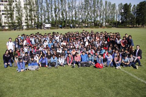 Un gran grupo de estudiantes posando juntos en un campo verde.