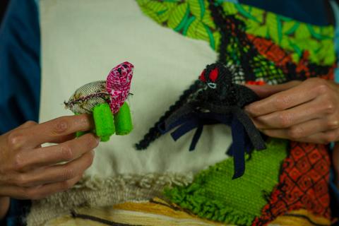 Dos figuras artesanales en las manos de una persona, una de ellas es un insecto colorido y la otra parece un pulpo.