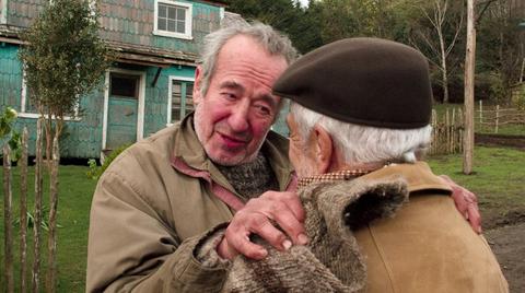 Dos hombres mayores comparten un emotivo encuentro en un entorno rural.