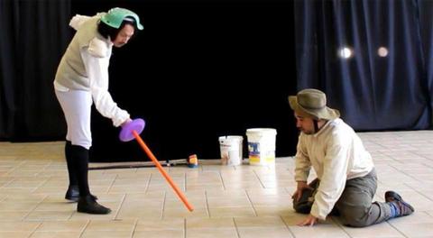 Dos personas en un escenario simulan un combate con espadas de juguete.