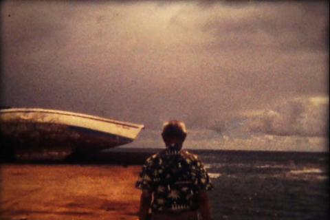 Una persona contempla un barco encallado en la orilla bajo un cielo nublado.