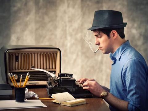 Un escritor concentrado utiliza una máquina de escribir mientras fuma un cigarrillo.