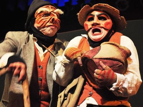 Dos actores con máscaras y vestimenta tradicional representan una escena teatral.