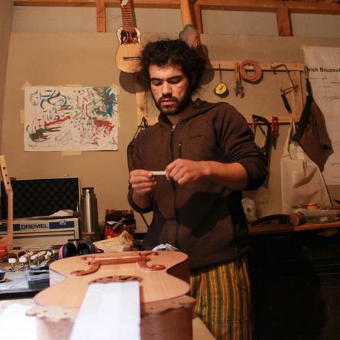 Un artesano trabaja en la construcción de un instrumento musical en un taller.