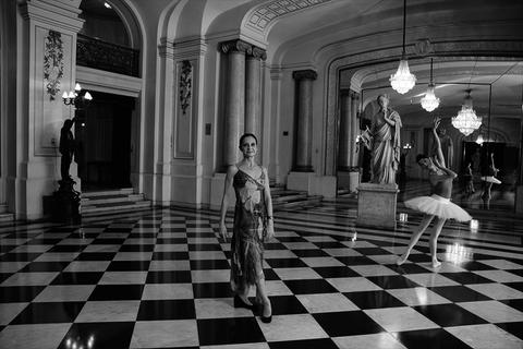 Una bailarina se presenta en un elegante salón decorado con estatuas y candelabros.