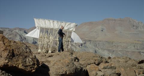 Una persona observa una estructura diseñada para volar en un paisaje montañoso.