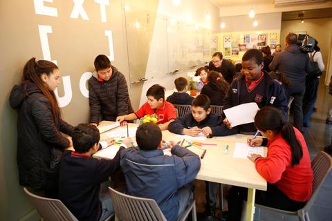 Un grupo de niños y adultos en un ambiente educativo trabajando en actividades artísticas en una mesa.