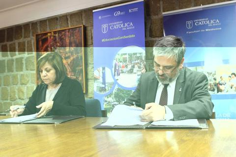 Dos personas firmando documentos en un entorno académico.