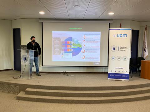 Un hombre está presentando en una conferencia frente a una pantalla con gráficos.