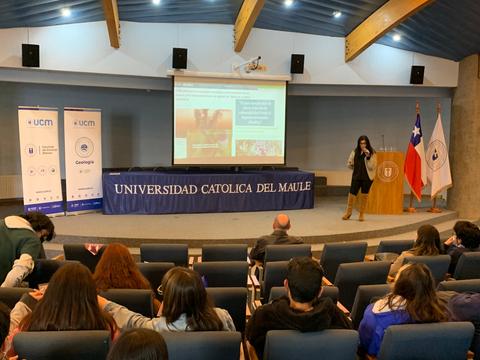 Una presentación en la Universidad Católica del Maule con un orador frente a un público sentado.