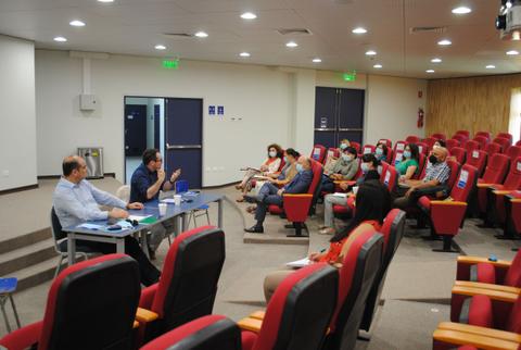 Un grupo de personas asiste a una charla en un auditorio con asientos rojos.