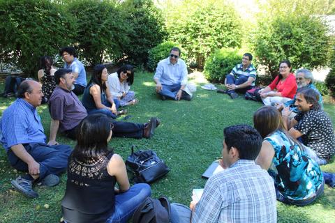 Un grupo de personas sentadas en círculo sobre el césped, disfrutando de un momento juntos al aire libre.
