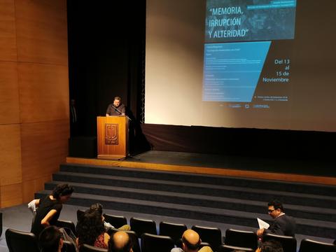 Una persona está hablando en un evento sobre memoria, irrupción y alteridad.
