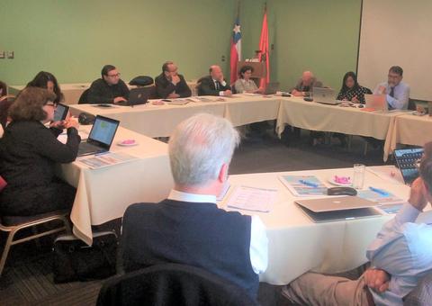 Una reunión de trabajo en una sala con varias personas sentadas alrededor de una mesa.