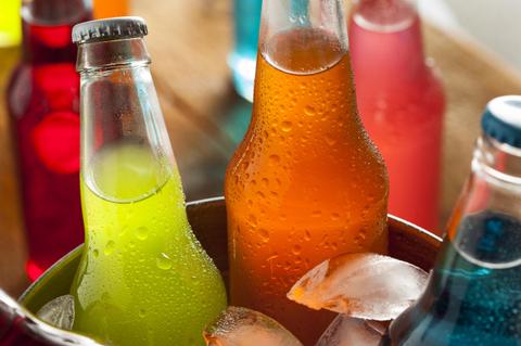 Botellas de refrescos de colores en un recipiente con hielo.
