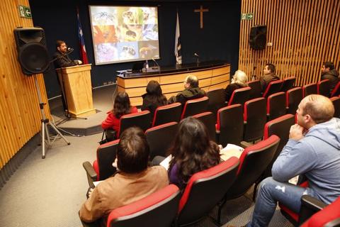 Una presentación en un auditorio donde se observa a un orador y a varias personas en la audiencia.