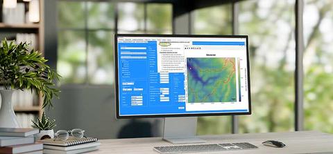 Una pantalla de computador muestra un software con un mapa y datos en un ambiente de oficina.