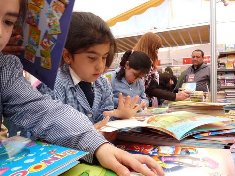 Un grupo de niños están explorando libros en una feria de lectura.