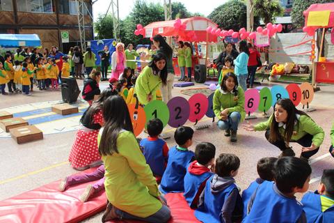Un grupo de niños y educadores participan en una actividad recreativa al aire libre con colores y números.