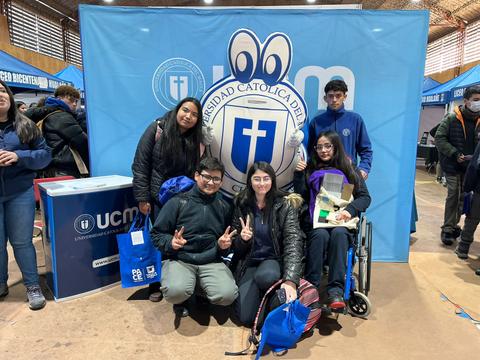 Grupo de estudiantes posando frente a un fondo de la Universidad Católica del Maule.