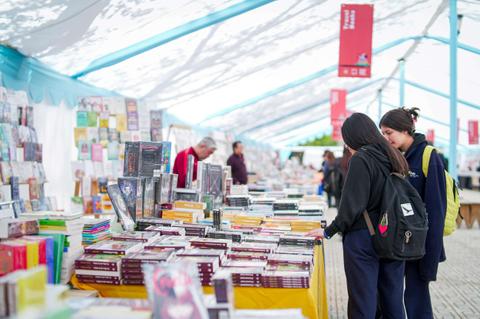 Dos chicas están mirando libros en una feria literaria.
