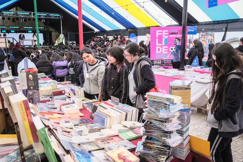 Un grupo de jóvenes explorando una feria del libro al aire libre en Chile.
