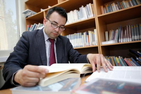 Un hombre que lee un libro en una biblioteca.
