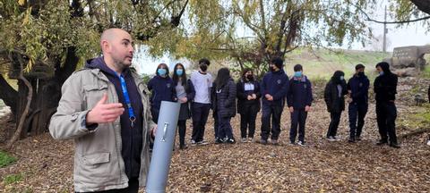 Un grupo de estudiantes escucha atentamente a un instructor en un entorno natural.