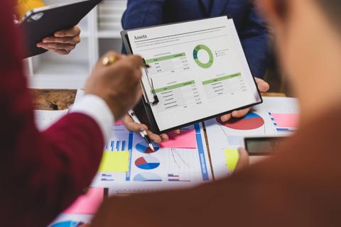 Grupo de personas analizando gráficos y datos financieros en una reunión.