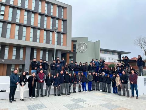 Un grupo grande de estudiantes posando frente a un edificio moderno.