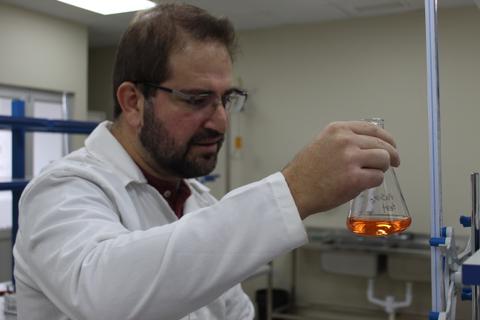 Un científico examina un matraz con un líquido anaranjado en un laboratorio.