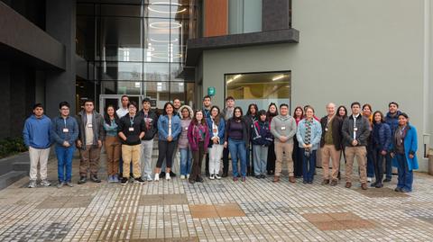Grupo de personas posando frente a un edificio moderno en una jornada de trabajo.