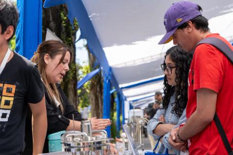 Una feria donde un grupo de jóvenes conversa y aprende sobre productos locales.
